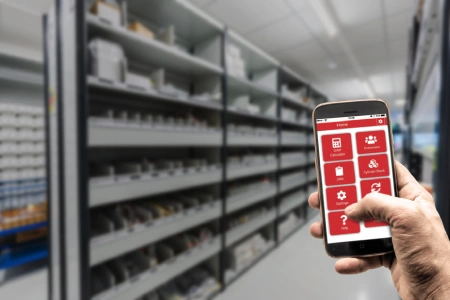 Close-up of a hand holding a smartphone displaying our cylinder manager app interface with multiple icons for features like calculator, customers, jobs, cylinder stock, settings, and help.